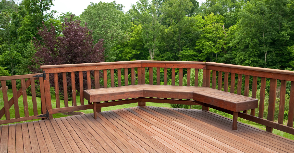 A wooden deck offering a serene view of lush green trees, creating a tranquil outdoor retreat connected with the vibrancy of nature.